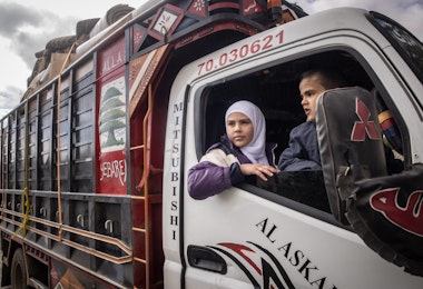 DAMASCUS, SYRIA - DECEMBER 21: 13-year-old Lana who was born in Syria and her brother 6-year-old Muhammad who was born in Lebanon wait in a truck carrying the family's possessions as their father Ahmed Muhammad Al-Nawa prepares papers to cross the border from Lebanon to Syria to return to his family’s home in the village of Harran for the first time in 10-years on December 21, 2024 in Damascus, Syria. 36-year-old Ahmed, was imprisoned and tortured by the regime for a year and half in the Mezzah Military Prison in 2012-2013, after his release, his wife and daughter were displaced from their home in the village of Harran, Eastern Ghouta, Damascus, during the Assad regime’s siege of the region in 2014. They fled to Lebanon where they have been living in a tent in the Hosh Al-Hareem camp for the past 10-years. Ahmed’s mother Umm Marwan stayed behind in Syria due to a heart condition that stopped her from travelling. While living in Lebanon, Ahmed and his wife had four more children that were born in Lebanon and have never meet their grandmother, other relatives or seen the family home. After the fall of the regime Ahmed decided to return home bringing all his possessions from Lebanon and giving his mother the chance to meet her grandchildren face to face for the first time. (Photo by Chris McGrath/Getty Images)
