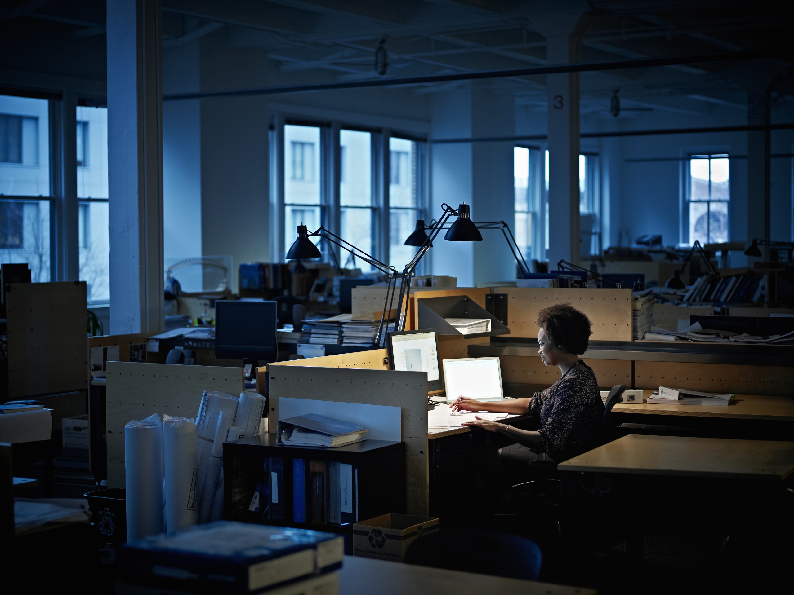 Businesswoman working at desk examining documents in empty office at night