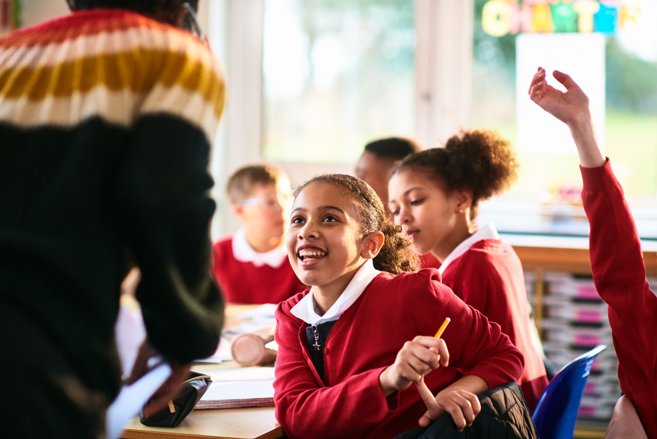 Children sitting at desk as teacher comes to the table, happiness, development, learning