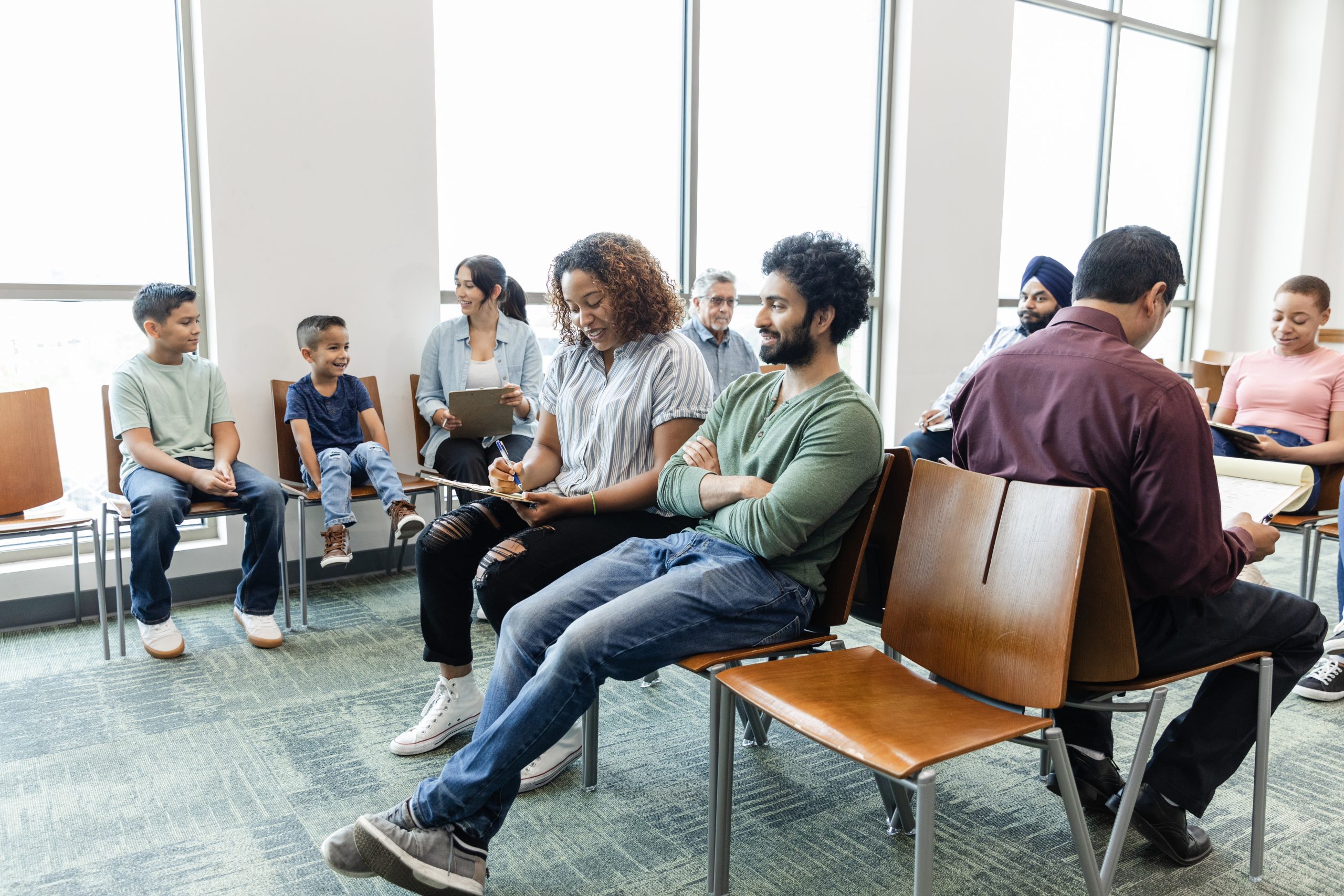 A large, multiracial group of people wait to see a medical professional.