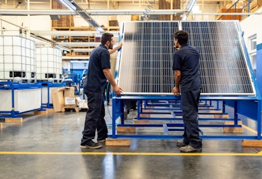 Green technology engineers installing solar panels at a manufacturing factory