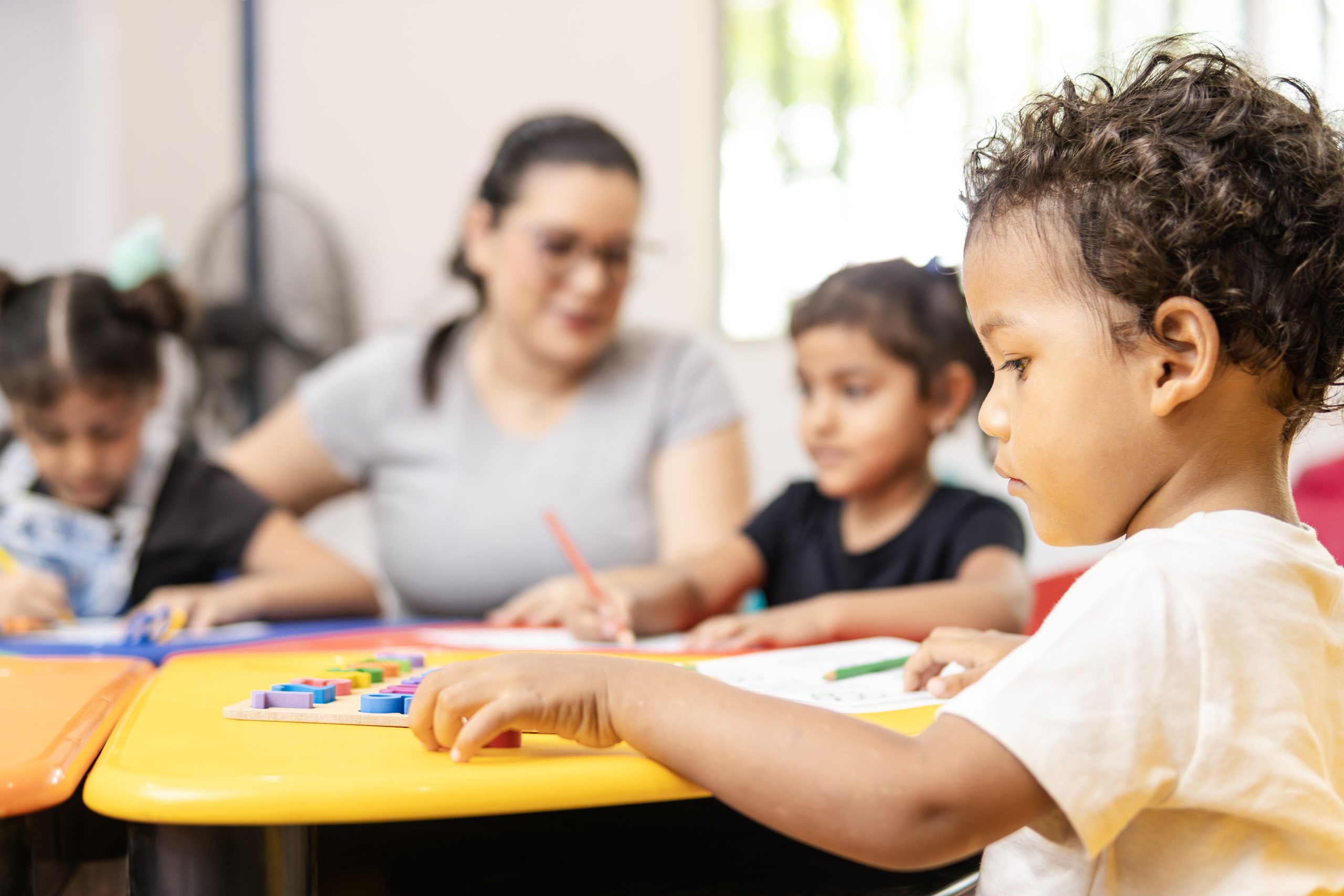 Latin american children learning the alphabet with their teacher in a kindergarten classroom