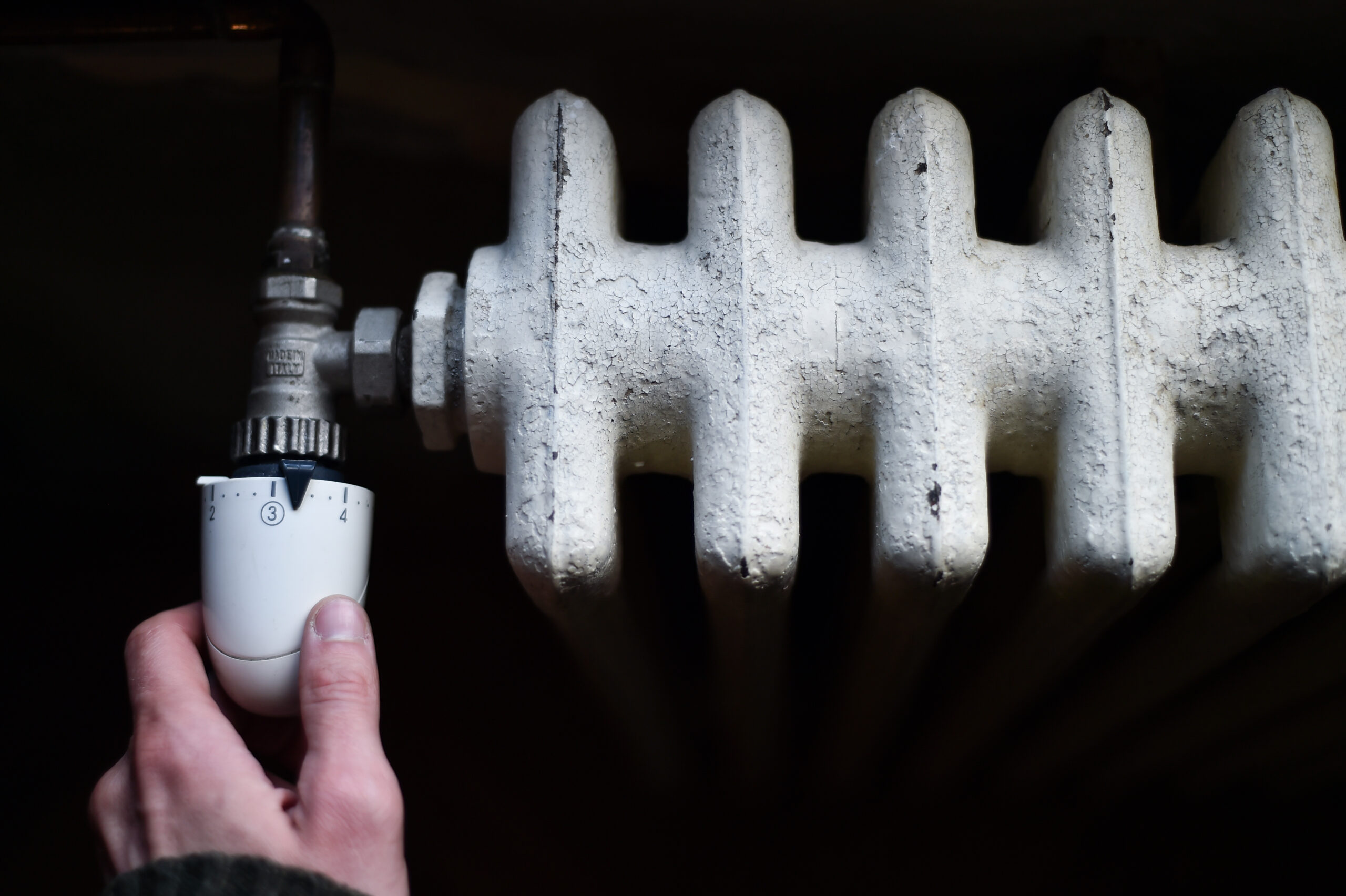 Detail with a hand checking the heat coming from a household radiator